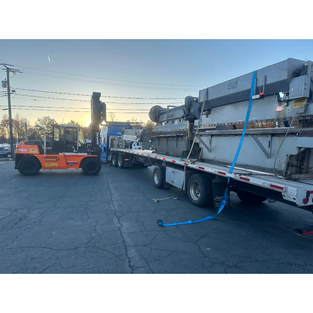 Heavy industrial equipment being loaded onto a trailer for surplus equipment liquidation.